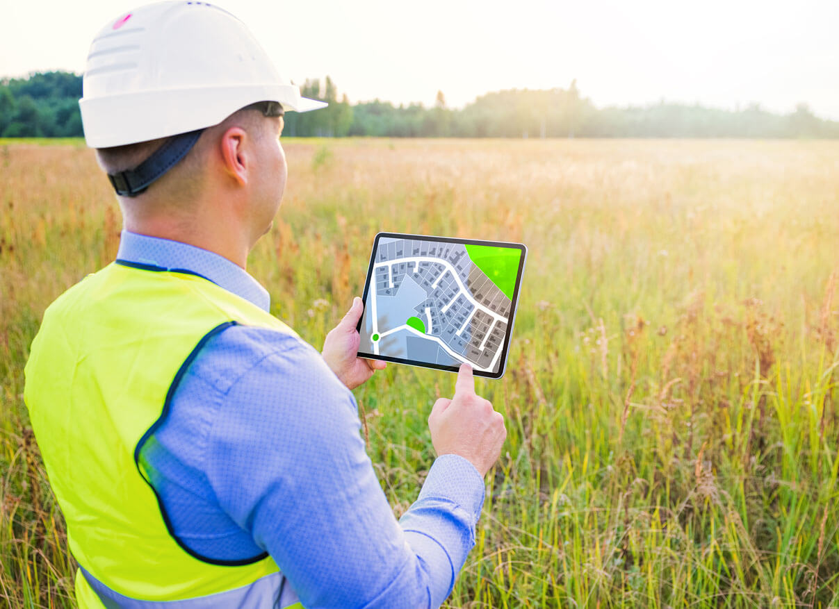 Man checking out building plan on a tablet standing in a field