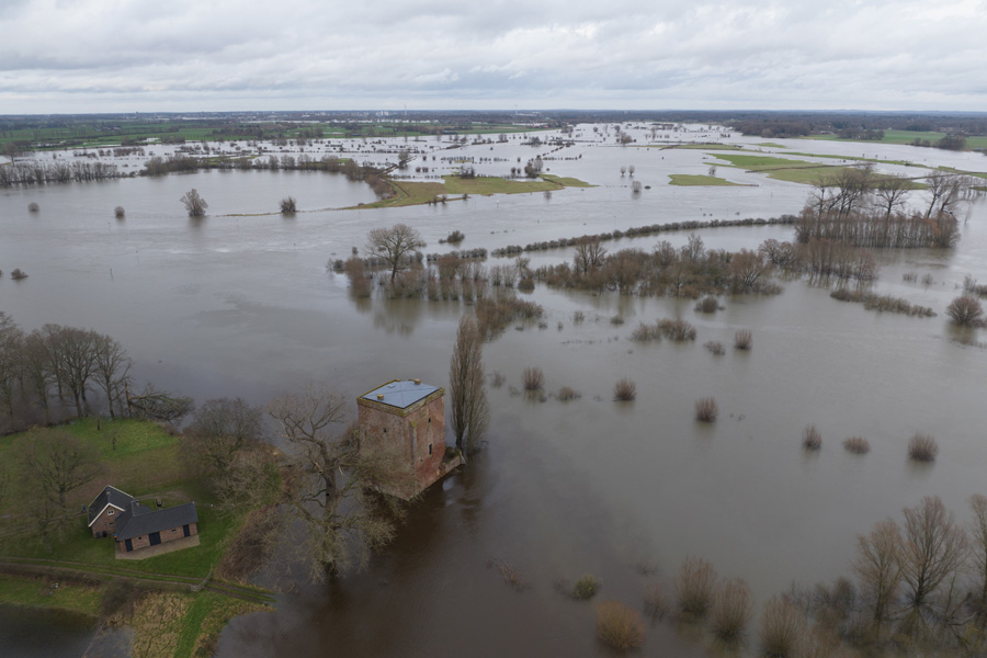 Overstroomde Nederlandse rivier met gebouwen die bijna in het water staan door de overstroming