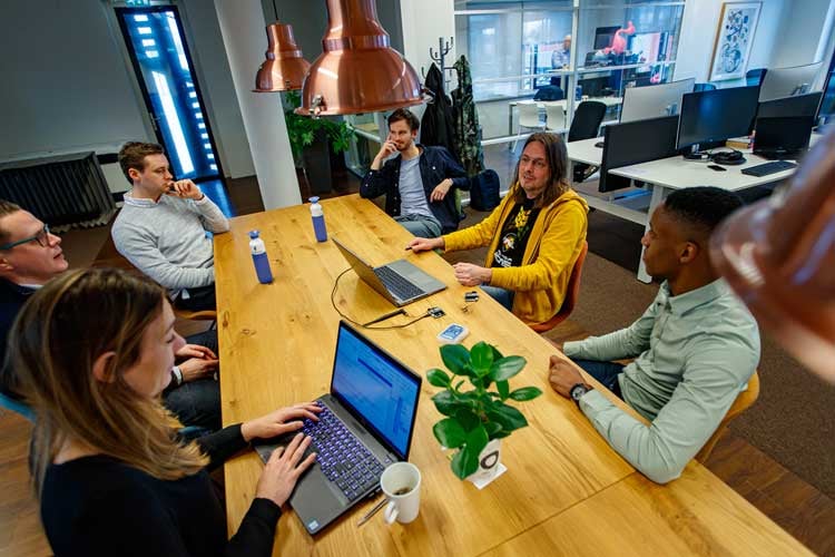 Zes teamleden overleggen aan eettafel