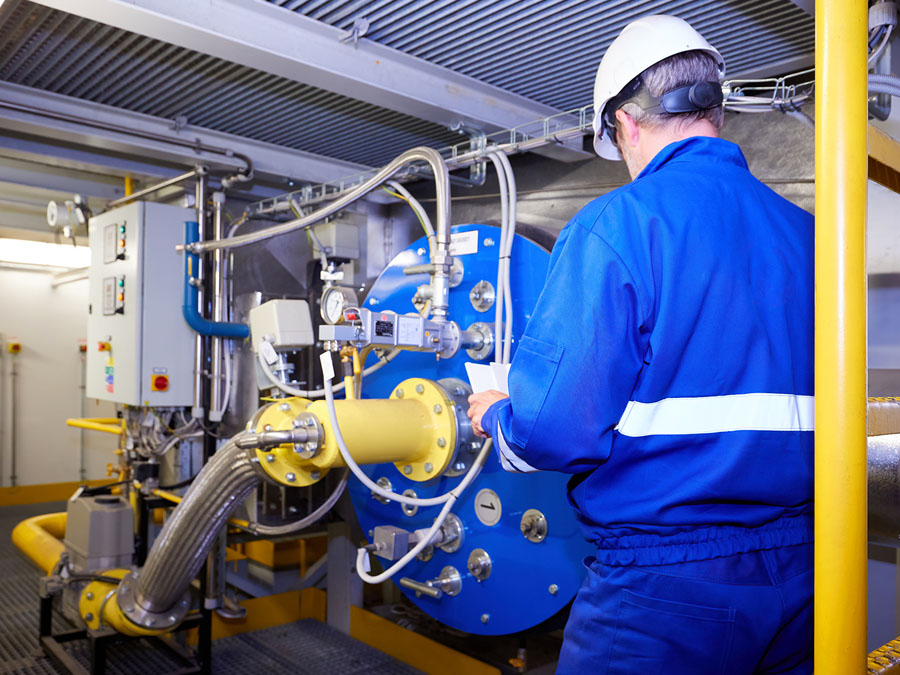 Maintenance worker in safety clothing checks heat installation in a technical room