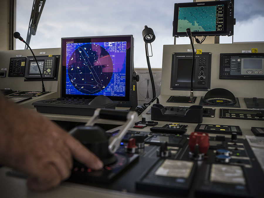 Main manœuvrant un bateau avec, au premier plan, une carte numérique pour la navigation